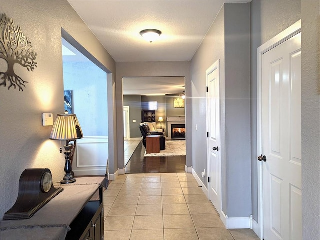 hallway featuring a textured ceiling and light tile patterned floors