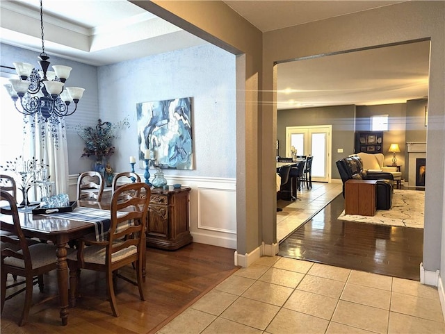 dining room featuring a raised ceiling, light tile patterned floors, and an inviting chandelier