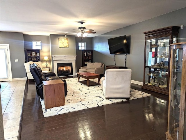 living room with dark wood-type flooring, a wealth of natural light, and ceiling fan