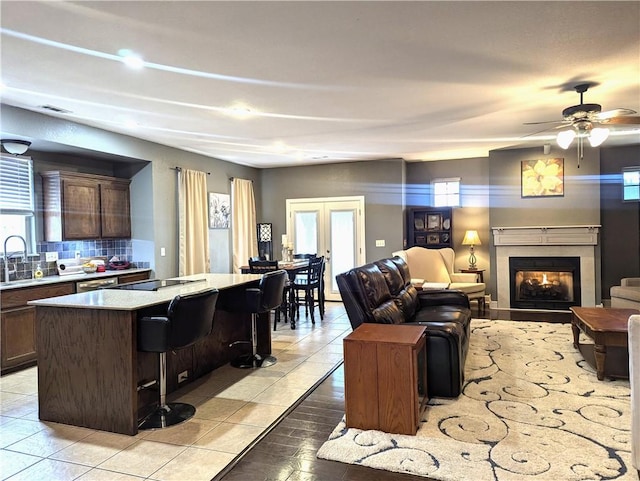 tiled living room featuring ceiling fan, french doors, and sink