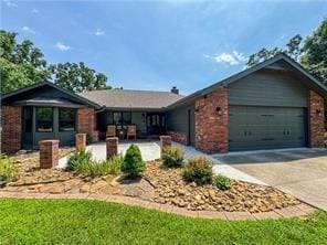 single story home with driveway, a garage, and brick siding