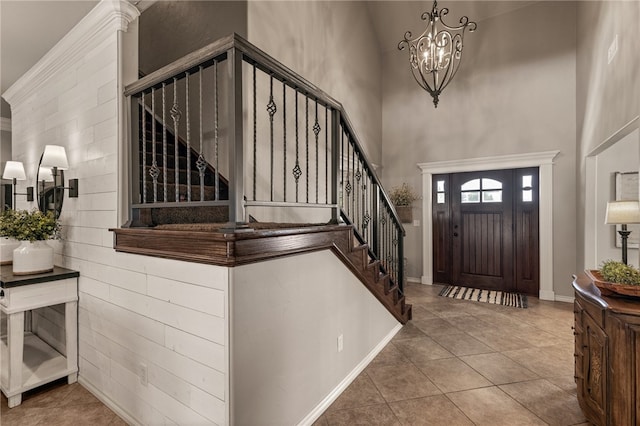 foyer featuring an inviting chandelier, a towering ceiling, and tile patterned floors