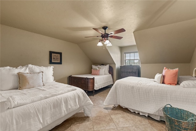 bedroom with vaulted ceiling, ceiling fan, light tile patterned floors, and a textured ceiling