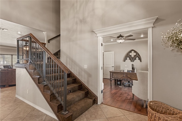 staircase featuring wood-type flooring, ornamental molding, and ceiling fan