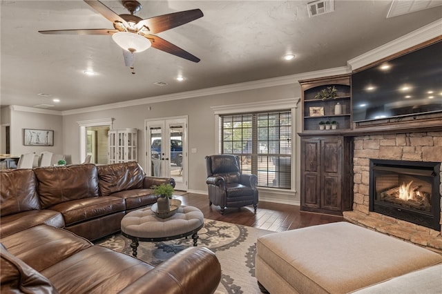 living room featuring ceiling fan, a stone fireplace, ornamental molding, and dark hardwood / wood-style flooring