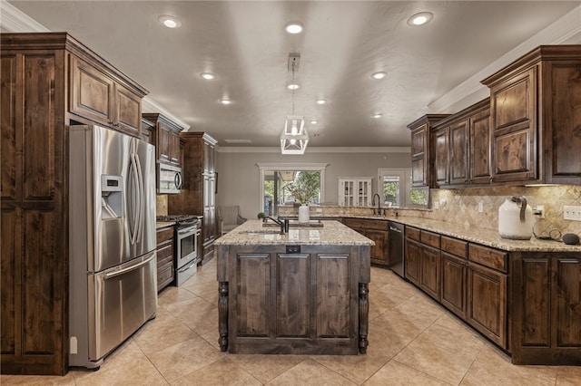 kitchen featuring pendant lighting, dark brown cabinets, a center island with sink, appliances with stainless steel finishes, and ornamental molding