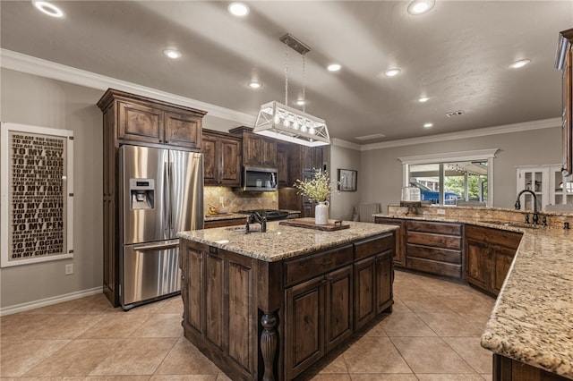 kitchen with decorative light fixtures, a center island with sink, stainless steel appliances, light stone countertops, and crown molding