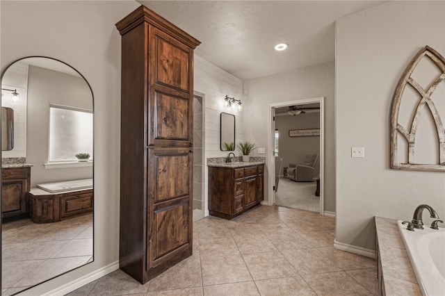 bathroom featuring tile patterned flooring, vanity, ceiling fan, and a relaxing tiled tub