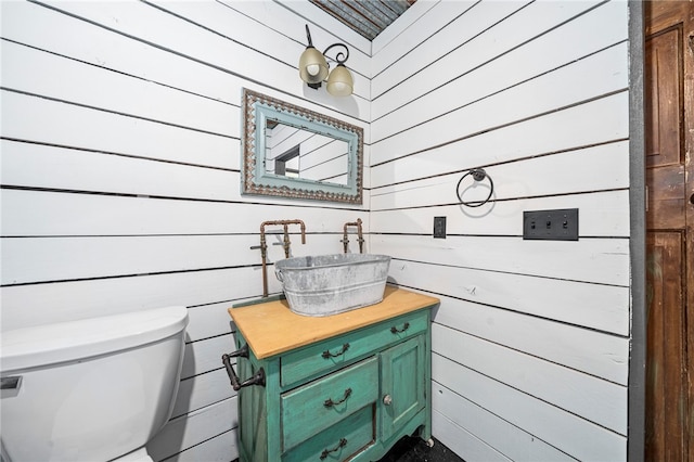 bathroom featuring wooden walls, vanity, and toilet