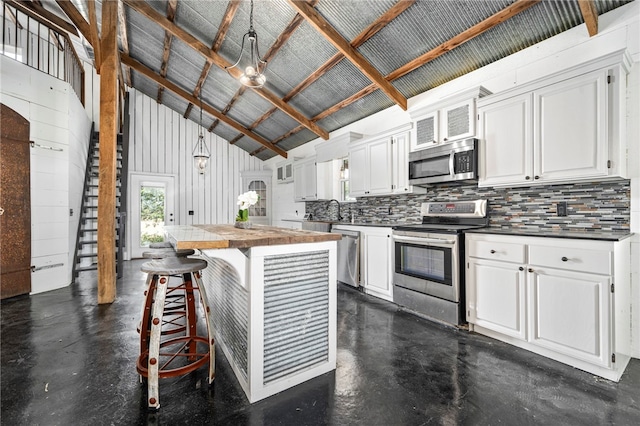 kitchen featuring white cabinets, stainless steel appliances, hanging light fixtures, and a kitchen island