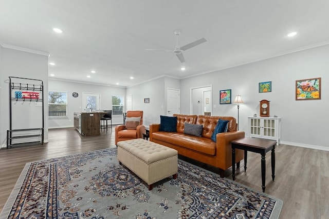living room with recessed lighting, baseboards, crown molding, and wood finished floors