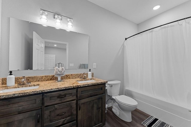 bathroom featuring toilet, wood finished floors, double vanity, and a sink