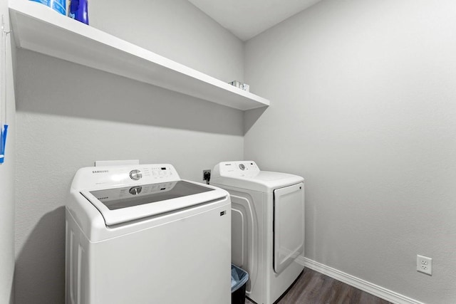 clothes washing area with washing machine and dryer, dark wood-style floors, laundry area, and baseboards