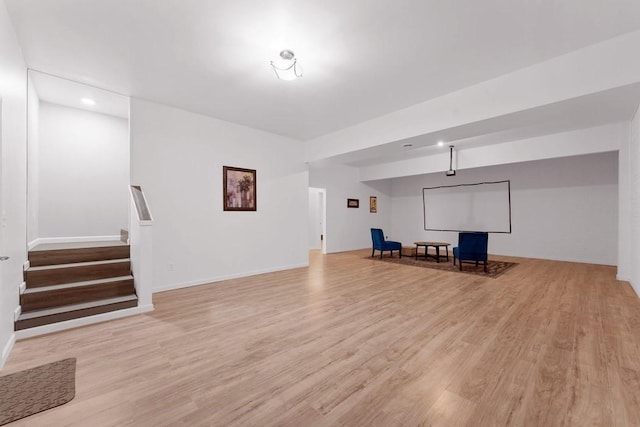 below grade area with recessed lighting, light wood-style floors, baseboards, and stairs