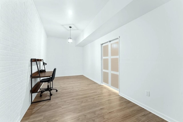 office area featuring wood finished floors, brick wall, and baseboards