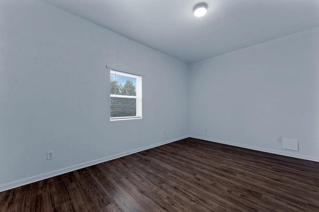 empty room featuring dark wood-type flooring and baseboards