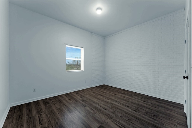 unfurnished room featuring brick wall and dark hardwood / wood-style flooring