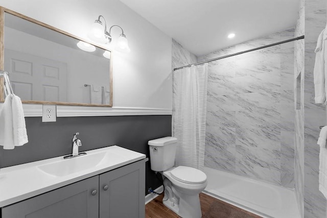 bathroom with a shower stall, vanity, toilet, and wood finished floors