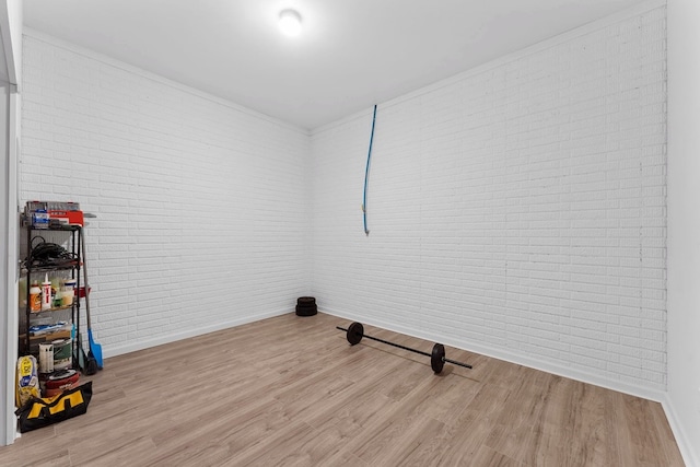 spare room featuring light wood-type flooring and brick wall