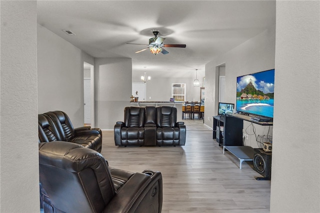 living room with ceiling fan with notable chandelier and light wood-type flooring