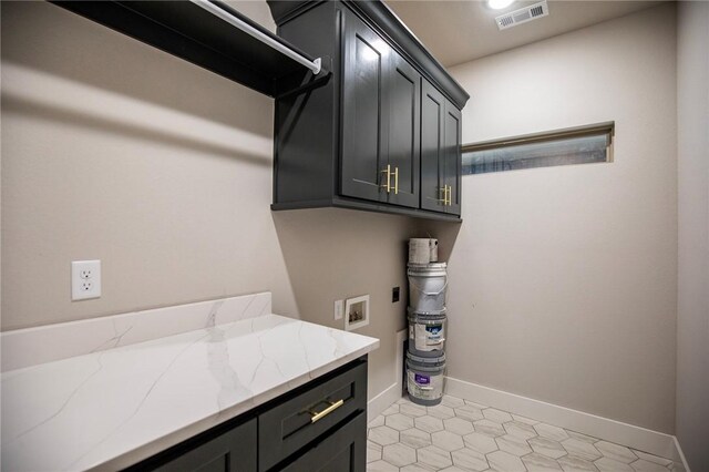 clothes washing area featuring cabinets, light tile patterned floors, and washer hookup