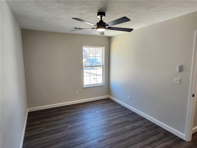 empty room featuring a textured ceiling, visible vents, a ceiling fan, baseboards, and dark wood finished floors