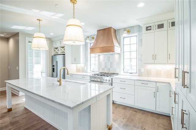 kitchen featuring sink, white cabinets, custom range hood, light hardwood / wood-style flooring, and appliances with stainless steel finishes