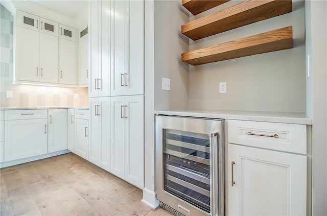 interior space featuring light hardwood / wood-style floors, beverage cooler, and white cabinets