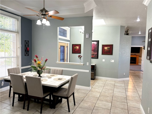 tiled dining space featuring a textured ceiling, ornamental molding, and ceiling fan