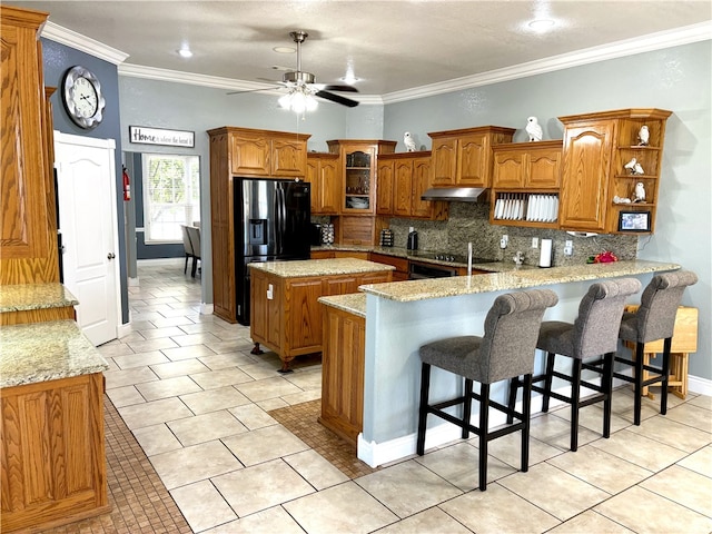 kitchen featuring kitchen peninsula, a kitchen island, a kitchen breakfast bar, ornamental molding, and ceiling fan