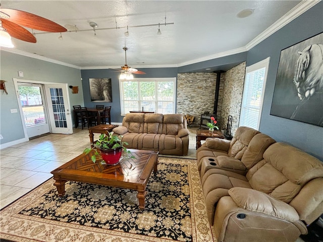 living room featuring light tile patterned floors, a wood stove, crown molding, ceiling fan, and track lighting