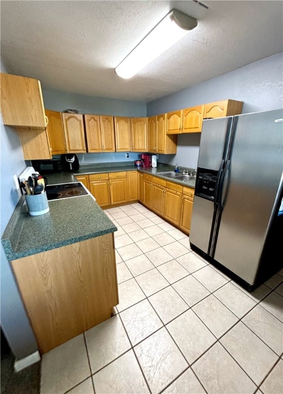 kitchen featuring a textured ceiling, light tile patterned flooring, sink, and stainless steel fridge with ice dispenser