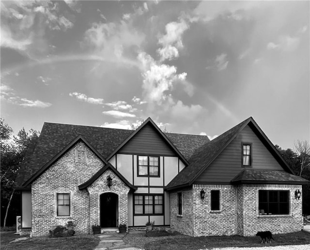 view of front of property featuring brick siding and roof with shingles