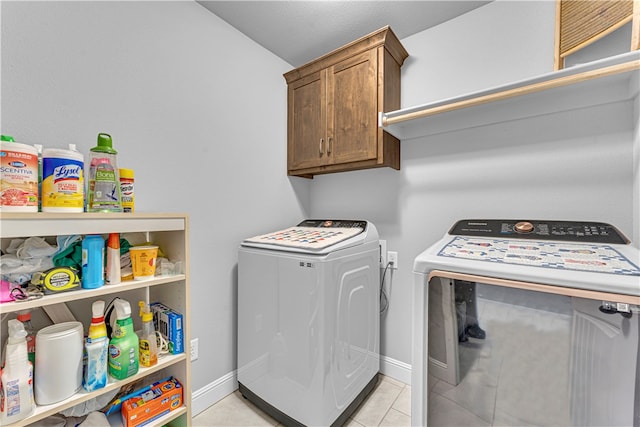 laundry room featuring washing machine and dryer, light tile patterned flooring, and cabinets