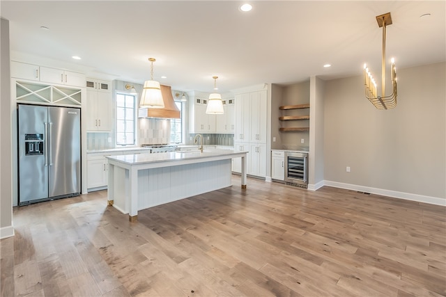 kitchen featuring premium range hood, beverage cooler, stainless steel appliances, and white cabinets