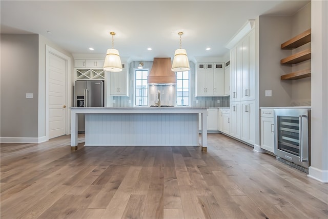 kitchen featuring a center island, beverage cooler, white cabinets, high end refrigerator, and decorative light fixtures