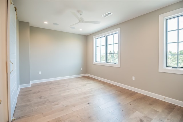 empty room featuring light wood-type flooring, a healthy amount of sunlight, and ceiling fan