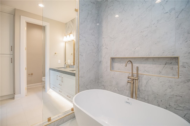 bathroom with tile walls, toilet, tile patterned floors, vanity, and a bathing tub