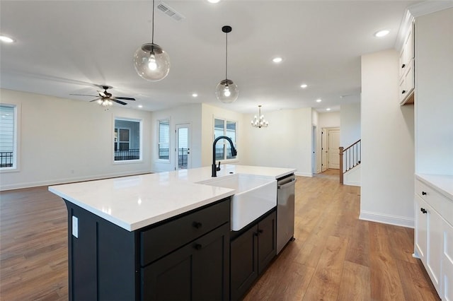 kitchen featuring pendant lighting, sink, a center island with sink, and white cabinets