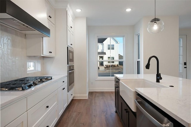 kitchen featuring white cabinets, stainless steel appliances, decorative light fixtures, and exhaust hood