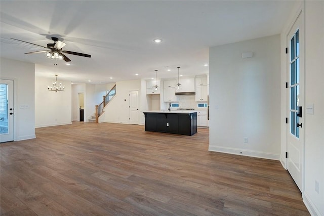 unfurnished living room featuring dark hardwood / wood-style floors and ceiling fan with notable chandelier