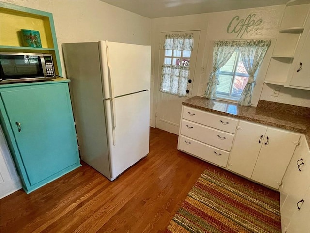 15 Linwood Ave, Eureka Springs, AR 72632 - kitchen with stainless steel microwave, open shelves, freestanding refrigerator, dark wood finished floors, and white cabinets
