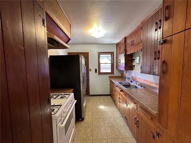 kitchen with a textured ceiling, sink, gas range gas stove, and range hood