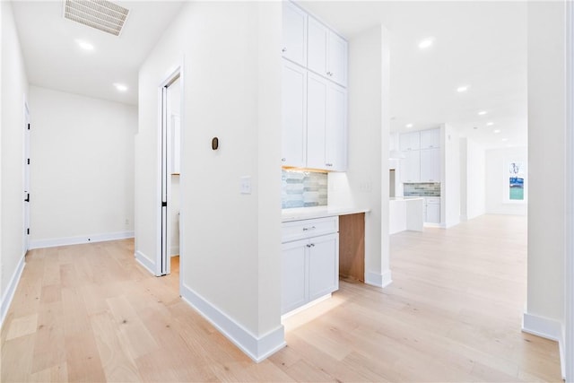 hallway with visible vents, baseboards, recessed lighting, and light wood-style floors