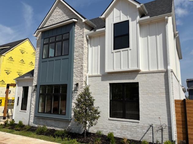 exterior space with board and batten siding, fence, and brick siding