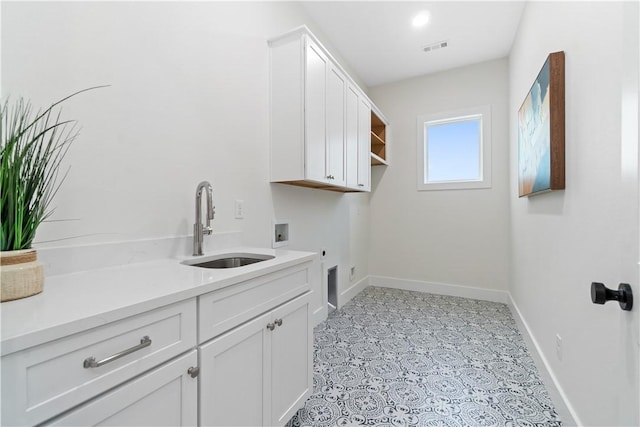 washroom with baseboards, a sink, washer hookup, and cabinet space
