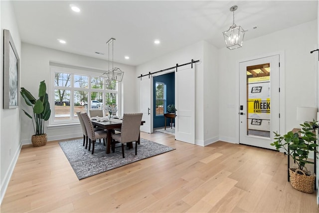 dining room with recessed lighting, a barn door, an inviting chandelier, and light wood-style flooring