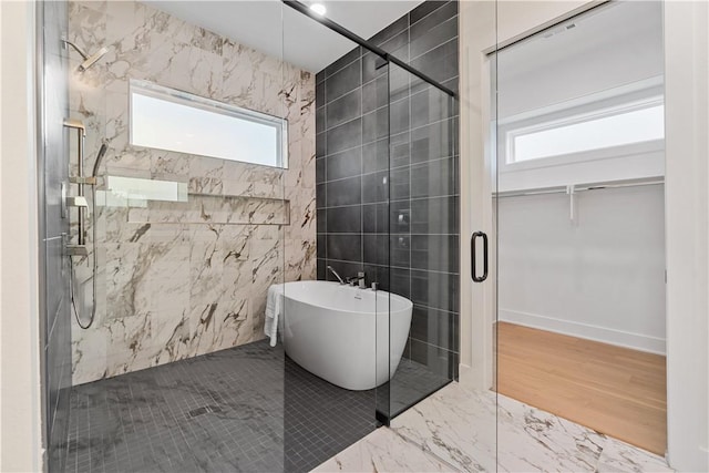 bathroom featuring tile walls, a freestanding tub, marble finish floor, and a stall shower