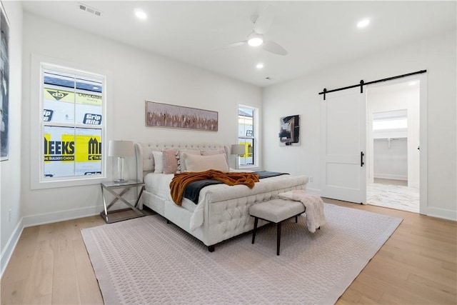 bedroom featuring a barn door, recessed lighting, visible vents, baseboards, and light wood-style flooring