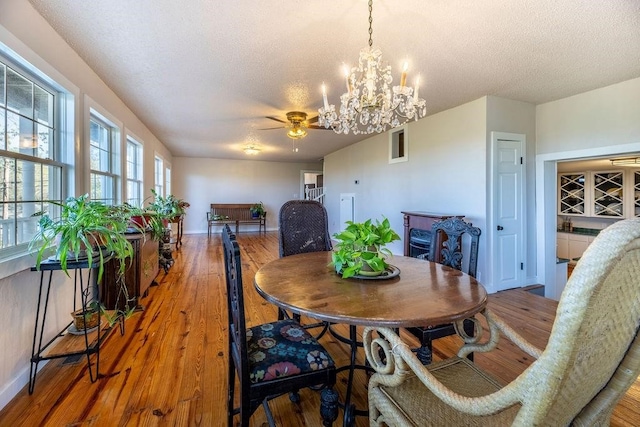 dining room featuring wood-type flooring, a textured ceiling, and ceiling fan with notable chandelier